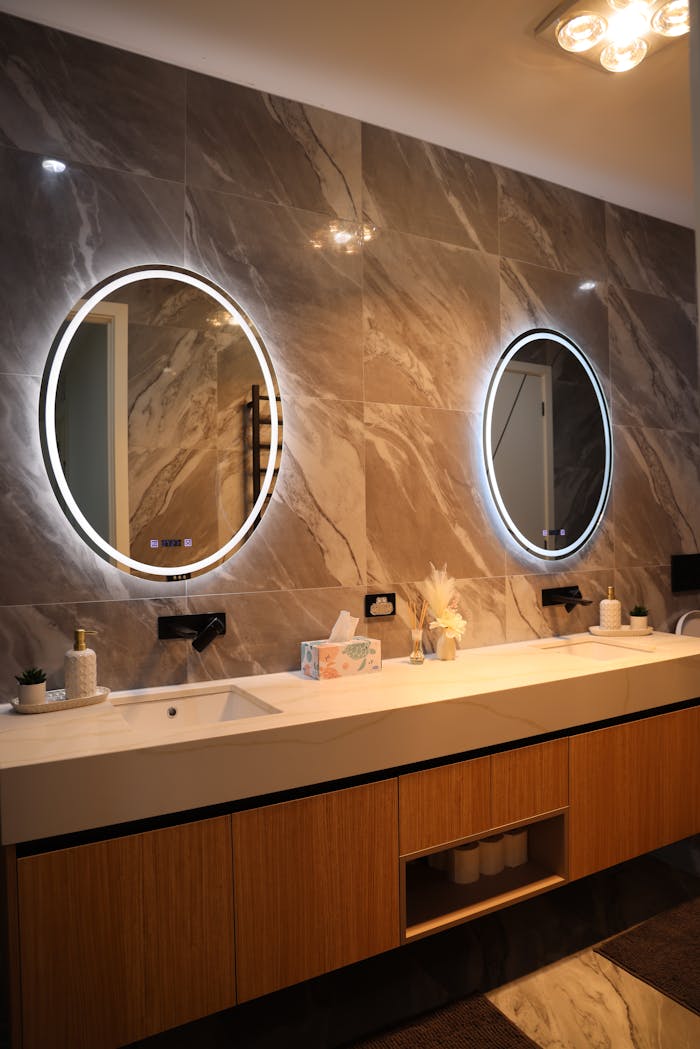 The Art of Drawing Readers In: Your attractive post title goes here Elegant bathroom interior featuring a double vanity with circular backlit mirrors, sleek design.